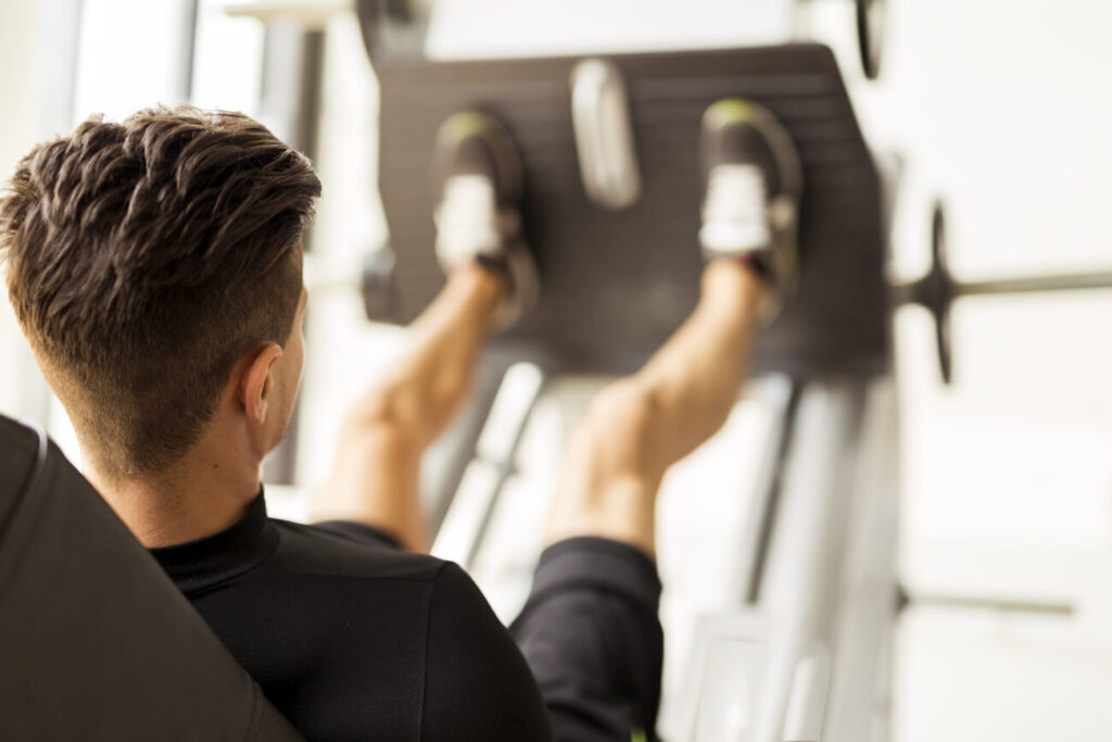 Wyprosty nóg na maszynie ćwiczenia wykonuje mężczyzna na siłowni